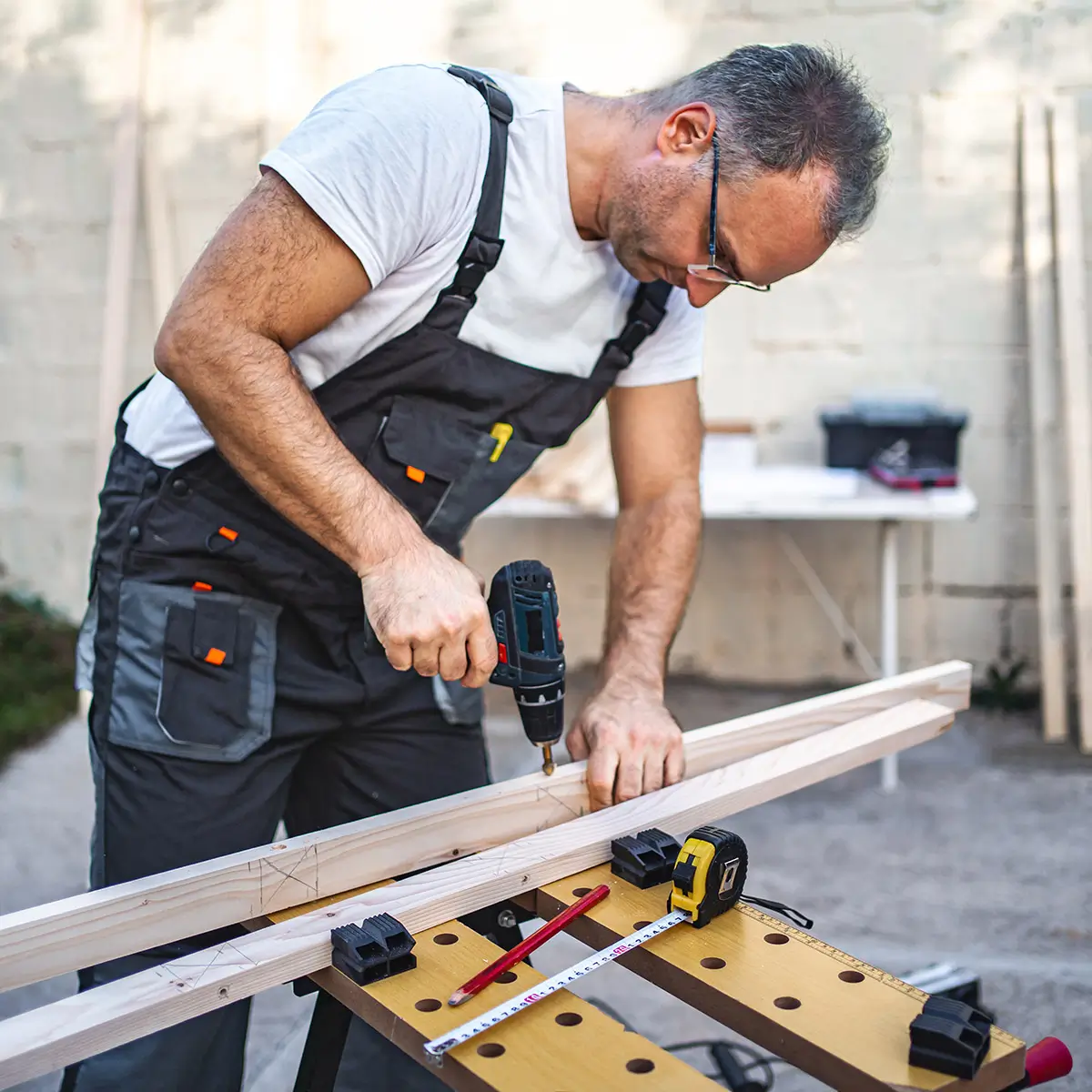 hausmeister am arbeiten mit bohrer und holz